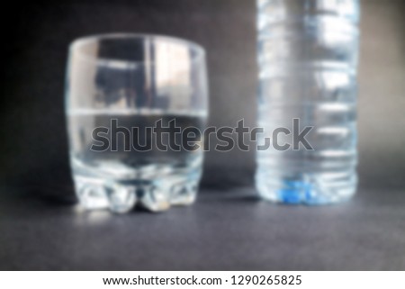 Blurred Glass of water with plastic bottle on black background.Water concept for health   