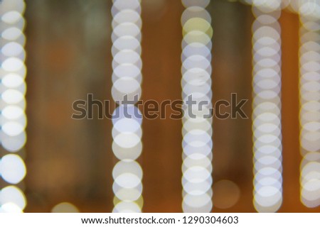 A blurred and defocused photograph of white light bulbs lined up.
