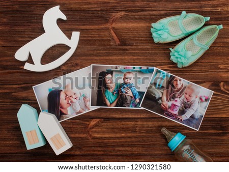 Mothers Day concept. Baby pictures, accessories and wooden toys on rustic wooden background with copy space. Top view, flat lay.