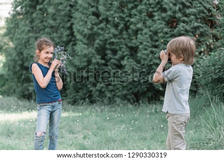 little boy takes a picture of his sister in the Park.