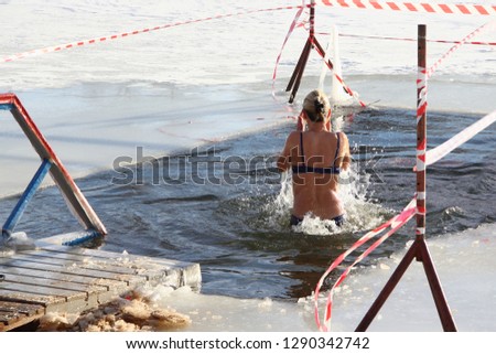 Walrus woman swimming in cold water in the ice hole in winter - winter sports, healthcare, HLS, rear view