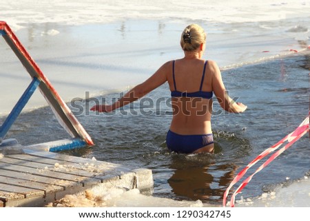 Beautiful walrus woman in swimsuit swimming in cold water in the ice hole in winter - winter sports, healthcare, HLS, , view from the back