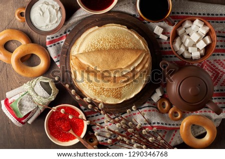 Shrovetide Maslenitsa Butter Week festival meal. Stack of russian pancakes blini with red caviar, fresh sour cream, cranberry jam and sushki. Rustic style, close up top view Royalty-Free Stock Photo #1290346768
