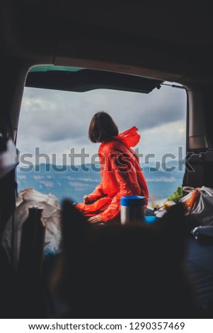 Vertical image of young traveller woman enjoying beautiful view of amazing nature landscape from car, vacation or journey concept, hipster girl admiring beautiful view while sitting in car with dog
