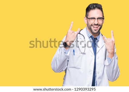 Handsome young doctor man over isolated background shouting with crazy expression doing rock symbol with hands up. Music star. Heavy concept.