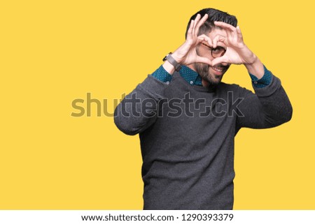 Young handsome man wearing glasses over isolated background Doing heart shape with hand and fingers smiling looking through sign