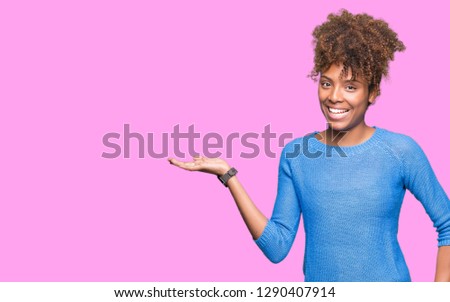 Beautiful young african american woman over isolated background smiling cheerful presenting and pointing with palm of hand looking at the camera.