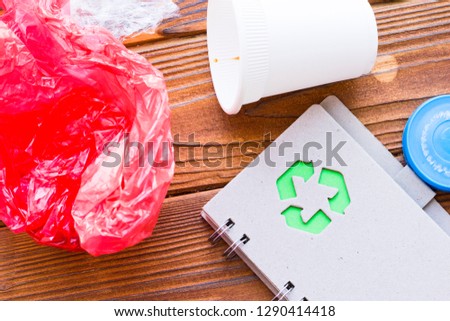 Environmental protection, ecology and recycling concept, notepad and garbage on dark wooden background top view closeup