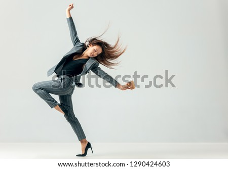 Happy business woman dancing and smiling in motion isolated over white studio background. Human emotions concept.  The businesswoman, office, success, elegance, grace, performer, flexible concepts