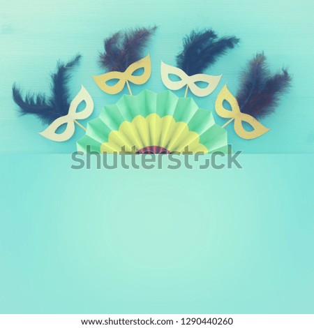 carnival party celebration concept with masks and colorful fan over blue wooden background. Top view