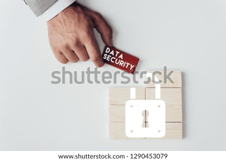 partial view of man holding brick with 'data security' lettering over wooden blocks with lock icon isolated on white