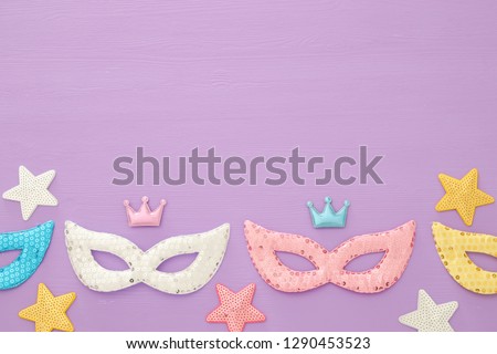 carnival party celebration concept with colorful masks over purple wooden background. Top view. Flat lay