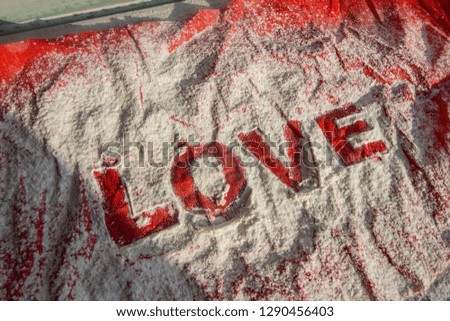 Poster with the word love in sweet still life. Written in sugar on red background. Crumpled paper. Vintage