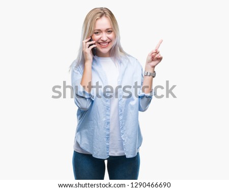 Young blonde woman talking using smarpthone over isolated background very happy pointing with hand and finger to the side
