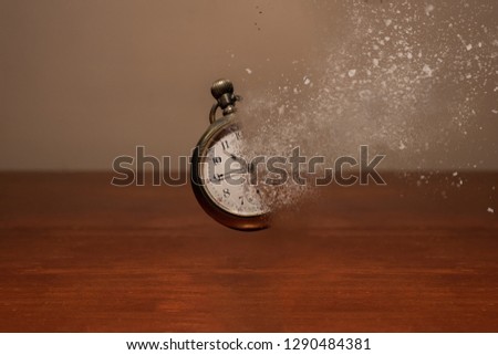 Old vintage pocket watch floating with a dispersion effect disintegrating it.