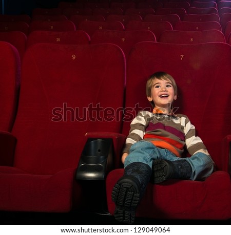 Smiling little boy watching movie in a cinema