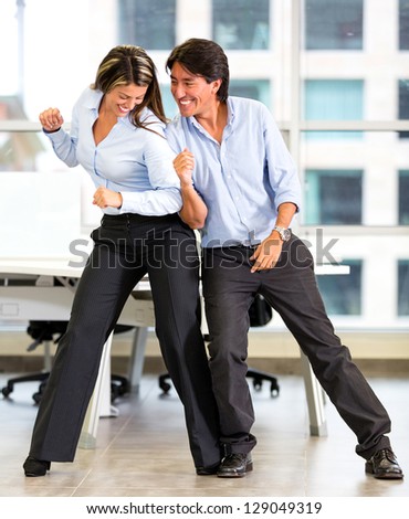 Competitive business couple wrestling at the office
