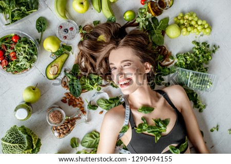 Beauty portrait of a woman surrounded by various healthy food lying on the floor. Healthy eating and sports lifestyle concept Royalty-Free Stock Photo #1290494155
