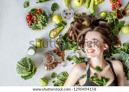 Beauty portrait of a woman surrounded by various healthy food lying on the floor. Healthy eating and sports lifestyle concept Royalty-Free Stock Photo #1290494158
