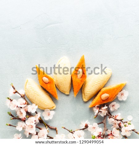 Novruz wreath mock up made of traditional Azerbaijan pastry shekerbura and pakhlava, beautiful tiny blossoms for spring equinox celebration on grey background, flat lay top view copy space for text
