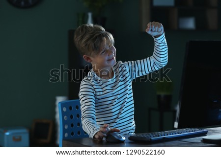 Happy little boy after winning computer game at home