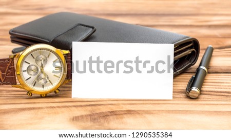 Blank business card with men's accessories on the table. 