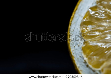 Half lemon slice detail on a black background, close up, isolated. Space for logo picture or advertisement text on the left side of the photography, macro shoot.