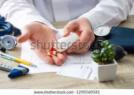 At doctors appointment physician shows patient capsules, which emptied into hand from container with focus on hand with drugs. Scene of prescription generic or OTC medications by doctor on visit Royalty-Free Stock Photo #1290560581