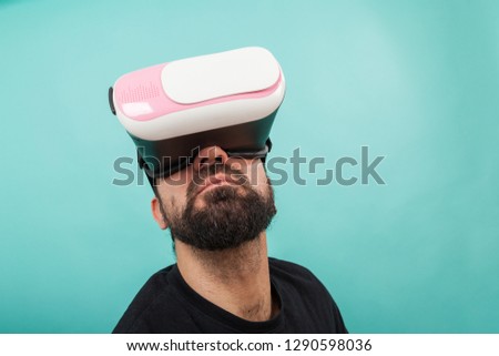 Bearded man use virtual reality glasses, goggles. Guy in VR headset is looking at interactive screen. Playing mobile game app on device.