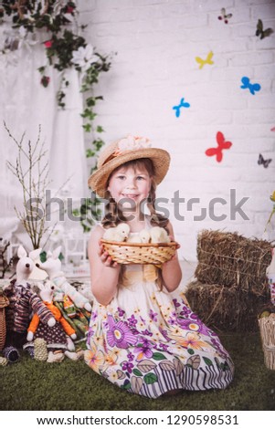 Studio photo of beautiful little girl with long blond hair with Easter chicken