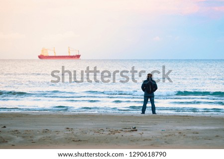 Adult man examines a cargo ship in the distance with solar flare