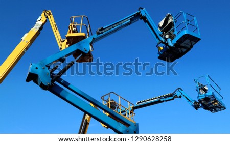 Aerial working platforms of cherry picker against blue sky Royalty-Free Stock Photo #1290628258