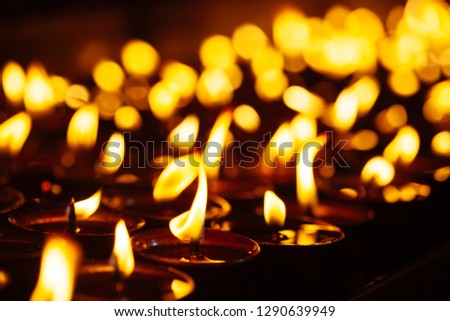 Many candle flames glowing in the dark with shallow depth of field