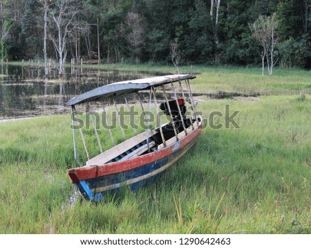 Small old boat in lakeside with fresh nature and green meadow background