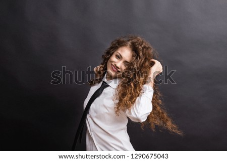 Young beautiful happy woman in studio, wearing white shirt and black tie.