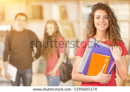 Portrait of a cute young student girl holding colorful notebook, isolated on background