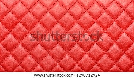 Close-up texture of genuine leather with rhombic stitching. Saturated red color. Luxury background