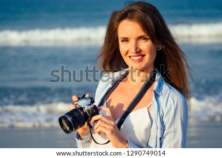 Hipster woman taking photos with retro film camera professional photographer on the beach.Traveling and photography.