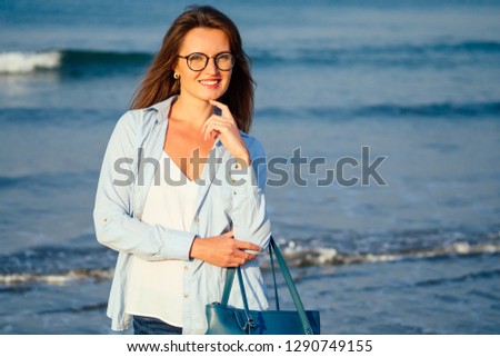 student business lady beach style .Woman tourist on tropical summer vacation wearing glasses, bag relaxing on travel holidays. Young lady luxury fashion blue shirt over white jersey top beachwear.
