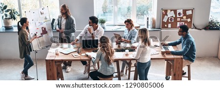 Sales report. Top view of two modern young colleagues conducting a business presentation while standing in the board room Royalty-Free Stock Photo #1290805006