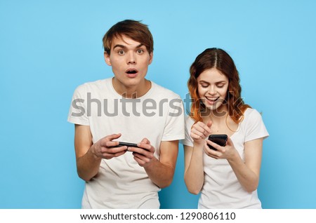 young people on a blue background are holding phones in their hands and the man is looking at the camera in surprise                               