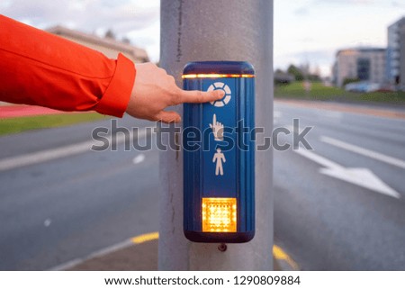 Photo of traffic light with pedestrian. Woman press on special button and wait change light to cross street