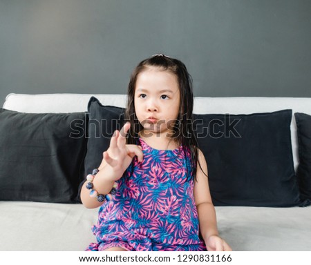 Smiling happy Asian girl with surprised face and funny excited face at home.4 years old little asian girl sitting on sofa at home.