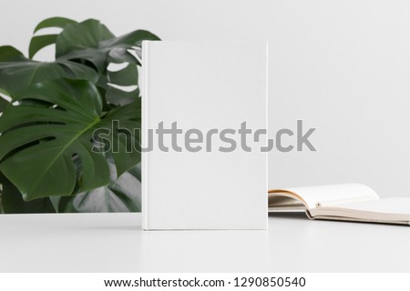 White book mockup with workspace accessories and a monstera plant. Royalty-Free Stock Photo #1290850540