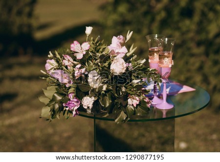 glass table with flowers and champagne glasses in the garden, preparation for the wedding ceremony