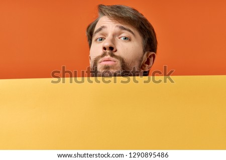 Cute bearded man looks out from behind a yellow mockup Poster