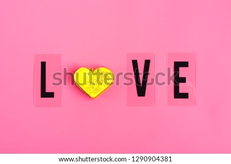 word love of black letters and heart shaped gingerbread with yellow icingon trendy pink background. Happy Valentine's Day, Mother's Day, March 8, World Women's Day holiday card concept. Flat lay.