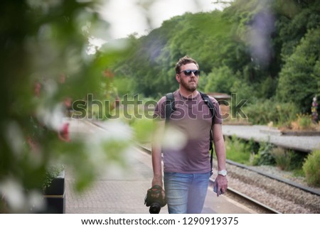 london, england, A male photographer wearing sunglasses walking along a vintage traditional train station platform in the British countryside. Amateur photographer. 