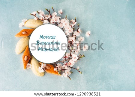 Novruz wreath mock up made of traditional Azerbaijan pastry shekerbura and pakhlava, beautiful tiny blossoms for spring equinox celebration,grey or blue background, flat lay copy space for text
