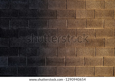 The texture of a brick wall made of blocks of imitation of natural stone, a delightful background with a gradient.         